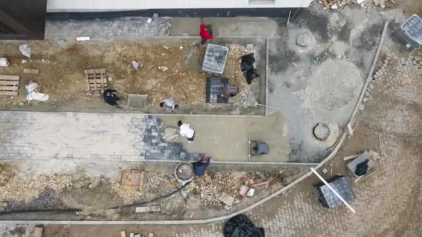 Vue aérienne Bâtisseurs pavage et aménagement paysager sur les chantiers de construction. Les artisans pavent trottoirs et sentiers pédestres. — Video