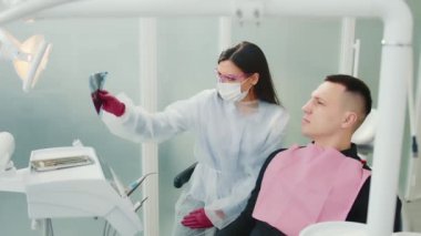 Doktor ve hasta, diş kliniğindeki dişlerin röntgenini inceliyor. İnsan çenesinin panoramik görüntüsü. Doktor bey. Diş hekimi hastanın sorunlu dişlerini gösteriyor.