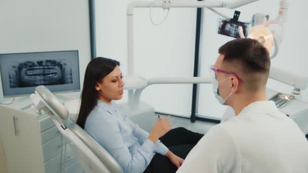 Kvinnlig tandläkare kommunicerar med patienten. Dialog på tandläkarens kontor. Rådfråga läkare. — Stockvideo