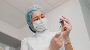 Hemşire aşıyı şırıngaya yerleştirir ve aşıya hazırlanır. Genç bir hemşire Coronavirus, influenza ve diğer hastalıklara karşı aşı olur..