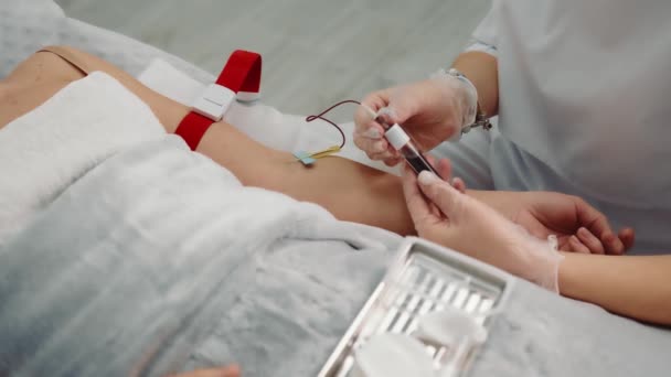Sjuksköterska som tar ett blodprov från en patient som ligger på en sjukhusavdelning. Blodsamling från en sjuk person på sjukhus i en cell. — Stockvideo