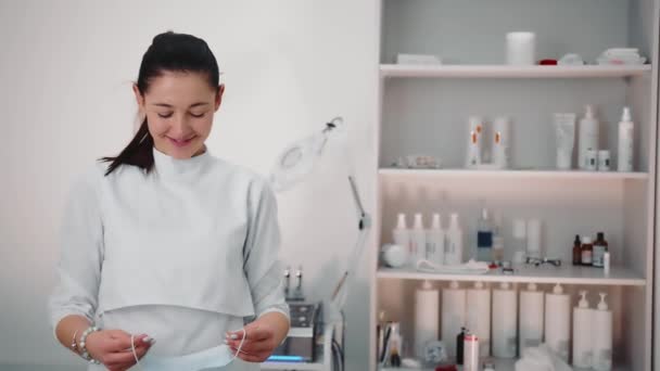 Az orvos védőmaszkot visel. Egy kozmetikus portréja egy szépségszalonban. A kozmetikus a kamerába néz.. — Stock videók