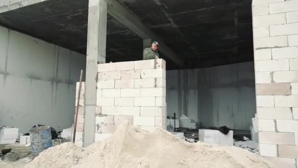 Construction worker builds a white brick wall. The builder builds brick walls — Stock Video