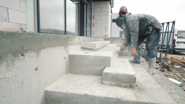 Un ingeniero de construcción que muele la superficie de una escalera de hormigón con la ayuda de herramientas. Trabajos de construcción. — Vídeos de Stock