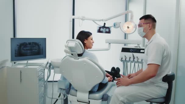 Стоматолог-мужчина общается с пациенткой в стоматологическом кабинете. концепция стоматологического здоровья. — стоковое видео