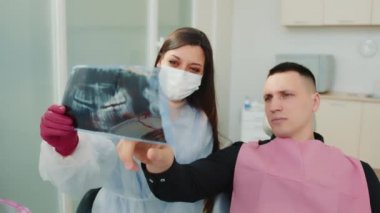 Diş hekimi ve hasta diş çenesinin hesaplanmış tomografisini inceler.