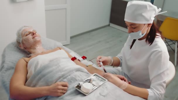 Muestra de sangre en un salón de belleza. El cosmetólogo toma sangre del paciente para crear plasma sanguíneo. — Vídeo de stock