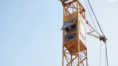 Bir vincin kokpitinde çalışan bir işçi. Vinçli bir ev inşa ediyorum..