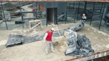 Erkek müteahhitler arabaya kum döker. İnşaat işi