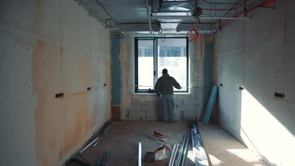 Un capataz de la construcción que instala ventanas y mide paredes y ventanas. — Vídeo de stock