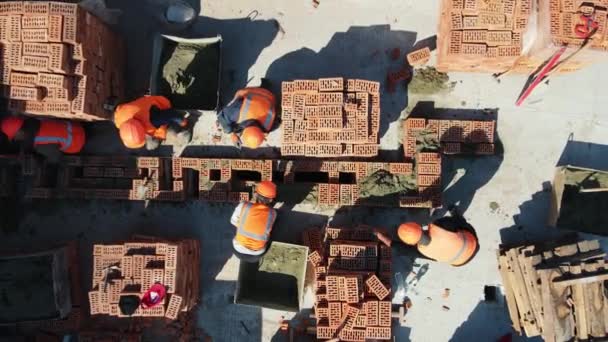 Aerea Vista dall'alto dei costruttori che costruiscono una casa. Costruttori stanno costruendo le pareti della casa. — Video Stock