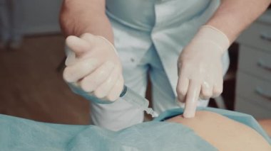 Ortopedist-travmatolog hastaların kalçalarına büyük bir iğne yapıyor. Derin enjeksiyon ablukası.