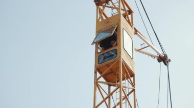 Bir vincin kokpitinde çalışan bir işçi. Vinçli bir ev inşa ediyorum..