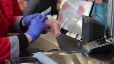 Satıcı, süpermarketteki kasada malları tarıyor. Kadın ellerini kapatın ve plastik poşetteki et ürünlerinin barkodlarını tarayın.