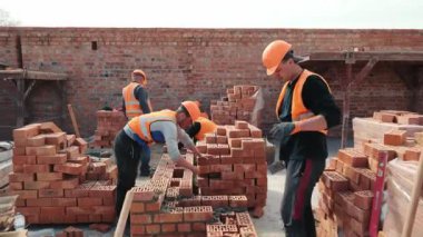 İnşaatçılar tuğla duvar örüyor. İnşaat işi. Efendiler tuğla döşeyip evin duvarını örüyorlar..