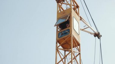 Bir vincin kokpitinde çalışan bir işçi. Vinçli bir ev inşa ediyorum..