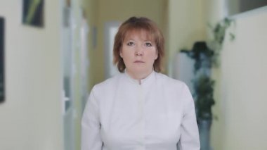 Kameraya bakan beyaz önlüklü bir kadın doktorun portresi..