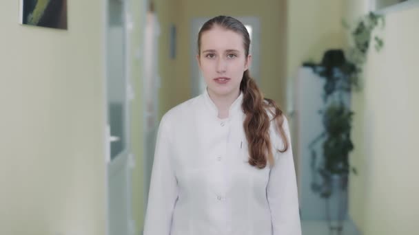 Retrato de una doctora con una bata blanca mirando a la cámara. — Vídeos de Stock