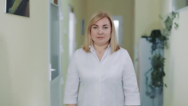 Portret van een vrouwelijke arts in een witte jas kijkend naar de camera. — Stockvideo