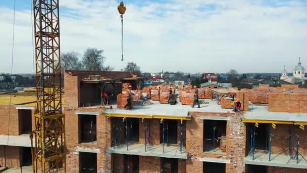 Volo sopra la costruzione di un edificio a più piani. I costruttori costruiscono una casa di mattoni e pavimenti in cemento. — Video Stock
