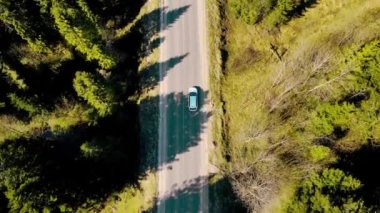 Üst beyaz arabadaki hava manzarası güzel dağlık arazide seyahat eder. Güzel bir manzarası olan asfalt bir yolda giden bir araba..