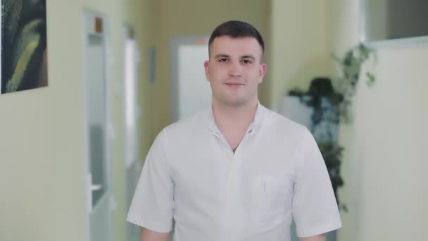 Porträtt av en ung terapeut läkare som står i en sjukhuskorridor och tittar på kameran. Läkare av kaukasiskt medborgarskap. — Stockvideo