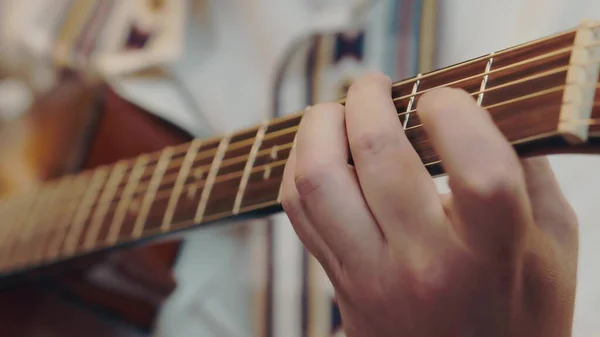 Male hand rearranges chords on acoustic guitar close up. — Stock Photo, Image