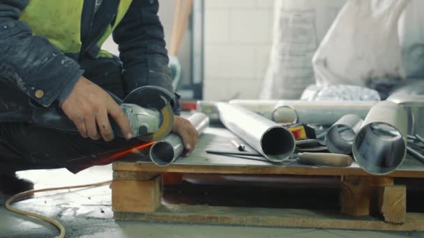 Cerrajero masculino trabajando en producción. Un hombre corta una tubería de metal con la mano sin protección. Chispas volando cortando una tubería de metal. — Vídeos de Stock