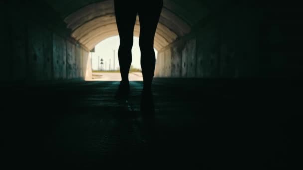 Donna che corre in un tunnel buio per incontrare la luce. Silhouette di una donna da dietro correre alla luce. — Video Stock
