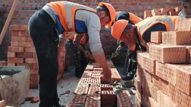 İnşaatçılar tuğla duvar örüyor. İnşaat işi. Efendiler tuğla döşeyip evin duvarını örüyorlar..