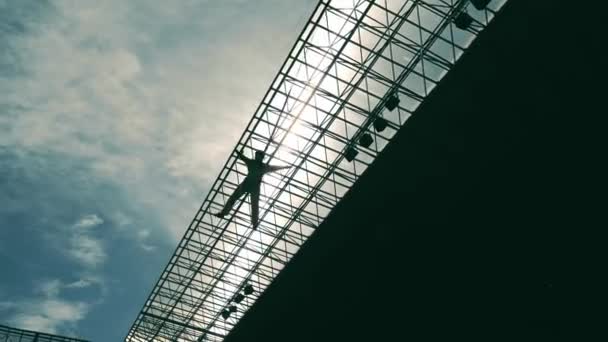 Une silhouette d'un homme suspendu au toit d'un bâtiment et accroché à une corde de sécurité. Un homme qui s'est cassé du toit d'une structure métallique et qui pend dans les airs. — Video