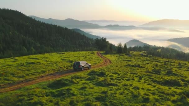 AERIAL Fliegen Fabelhafte Morgenröte im Hochland. Morgen in den Bergen und Rum, der das Tal zerbrach. Ein großes Touristenauto bewegt sich auf einem Feldweg. Reise in die Berge. Drohnenflug rund um den Jeep. — Stockvideo