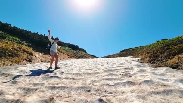 Escursionista donna in estate sulla cima di una montagna passa attraverso la neve. La donna si addormentò nella neve. Escursioni in montagna e neve in estate — Video Stock