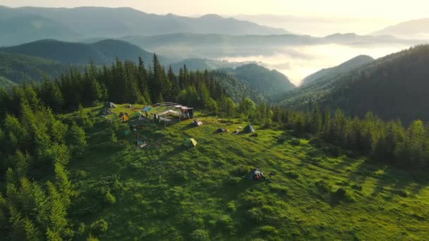 Vuelo aéreo sobre una tienda de campaña en lo alto de las montañas al amanecer. Increíble paisaje en la cima de la corteza al amanecer y niebla en las montañas. — Vídeo de stock