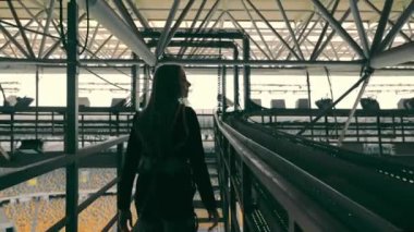 Bir binanın tepesindeki metal yapılarda hareket eden endüstriyel bir kadının silüeti..