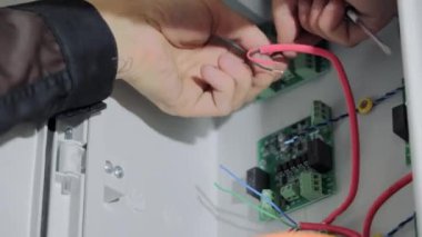 Ukrayna Lviv. 10.07.2021 Elektrikçi testçisi elektriksel temasları yakından kontrol ediyor. Aygıtların elektrik panelindeki bağlantılar.