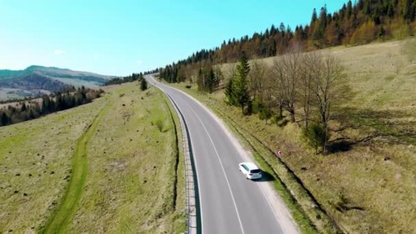 Vue aérienne voiture blanche se déplace dans un beau terrain montagneux. Une voiture conduisant sur une route asphaltée avec un beau paysage. — Video