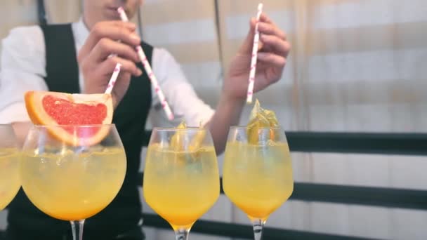 De barman heeft alcoholarme cocktails bereid. Close-up van een ober die buisjes in glazen stopt met een cocktail. — Stockvideo