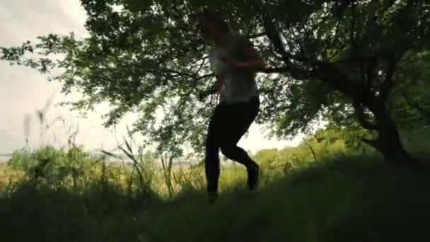 Meisje rent tussen bomen, jong meisje springt over een boomtak, jong meisje rent, atleet rent in het bos, meisje rent onder boomtakken — Stockvideo