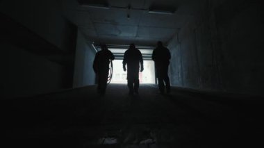 Işıkta çalışan üç yapım mühendisinin silueti. Bir inşaat şirketinin çalışanları sokaktaki yeraltı otoparkından çıkıyorlar..
