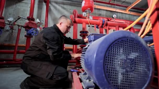Un ingeniero de estación de bombeo de agua repara el motor del compresor de suministro de agua. — Vídeos de Stock