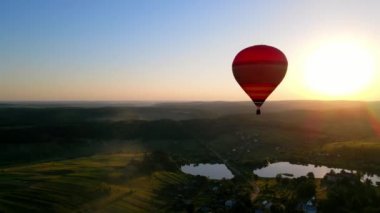 Gün batımında ufkun ortasında bir balon uçar. Güneşte uçan bir balonun resimli hali. Güzel manzara: alacakaranlık, balon, göl ve günbatımı