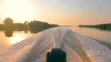 Tuna nehir yatağında gün doğumunda hareket eden bir motorlu teknenin görüntüsü. Sürat teknesi ve motor yüksek hızda çalışıyor. Güzel bir tekne manzarası ve gün doğumu.