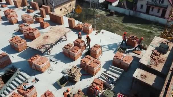 Bovenaanzicht vanuit de lucht Bouw van een huis van rode baksteen. Bouwvakkers bouwen een stenen huis met meerdere verdiepingen. — Stockvideo