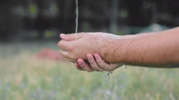 Mężczyzna myje brudne ręce pod bieżącą wodą na ulicy. Mycie rąk do góry — Wideo stockowe