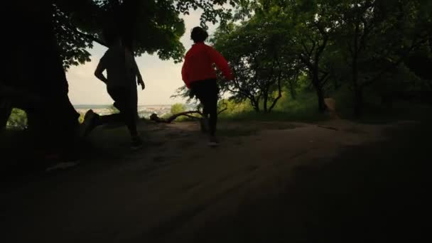 Bambini corrono nel bosco, corsa mattutina di tre bambini, una ragazza e due ragazzi corrono, jogging mattutini per bambini, bambini corrono nel bosco, vista posteriore, vista sulla città — Video Stock