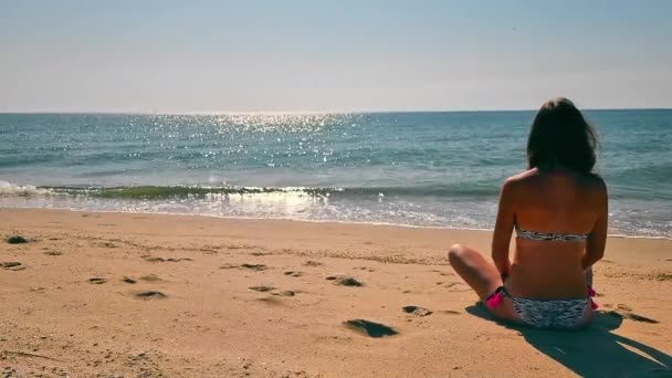 Donna seduta vicino al mare e guardando in lontananza in mare. Guardando al futuro durante una vacanza sulla spiaggia di sabbia. — Video Stock