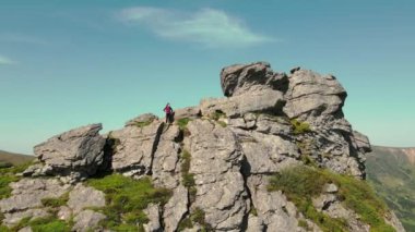 Genç bayan turist arkasını dönmüş ve dağların güzelliğine bakıyor. Dağların resimli güzelliği. Hava görüntüsü. Uçurumun kenarında duran kadın