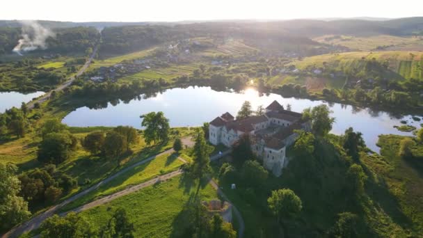 Hrad při západu slunce u jezera. Starobylý hrad v malebném místě. Hrad, jezero a malá vesnice, kouř se šíří po obzoru. — Stock video