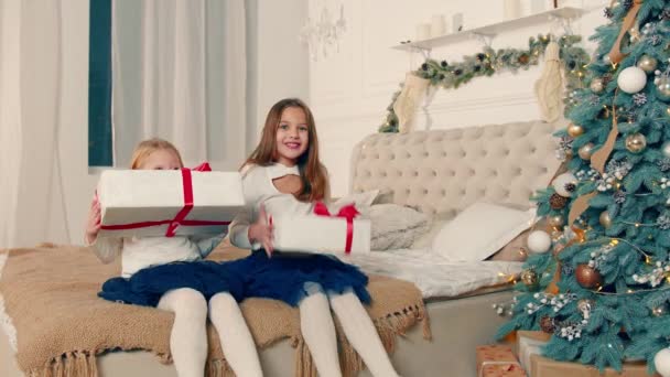 Niñas felices que recibieron regalos de Navidad. Dos niños pequeños están contentos con regalos en cajas. — Vídeo de stock